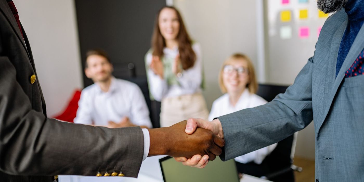 Two business partners shaking hands across a meeting table